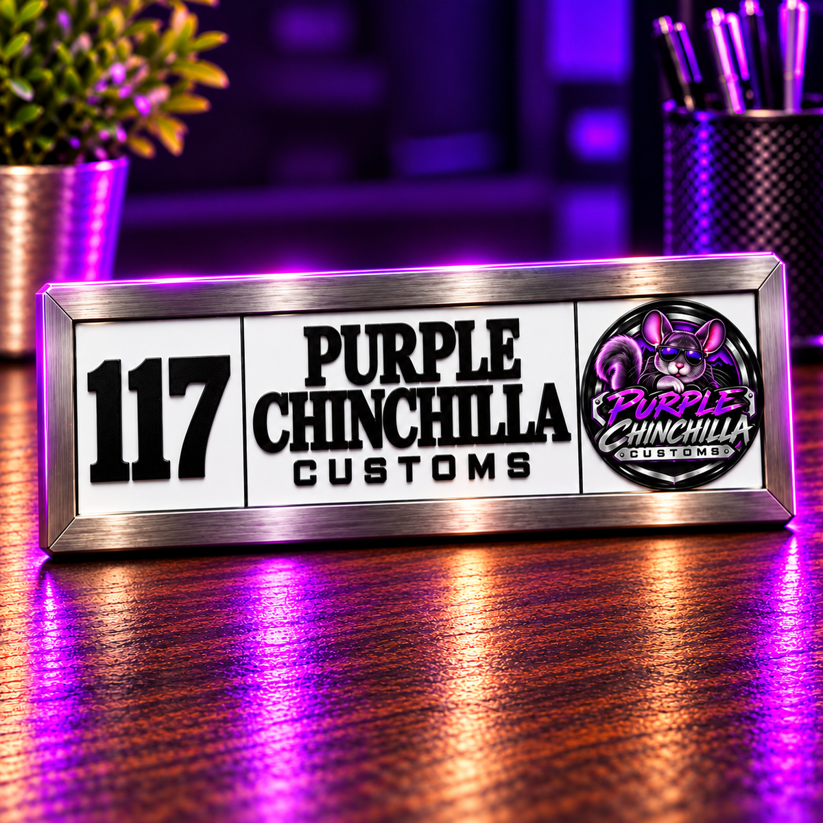 Custom 117 Room ID plaque with Purple Chinchilla Customs emblem on a purple-lit wooden desk