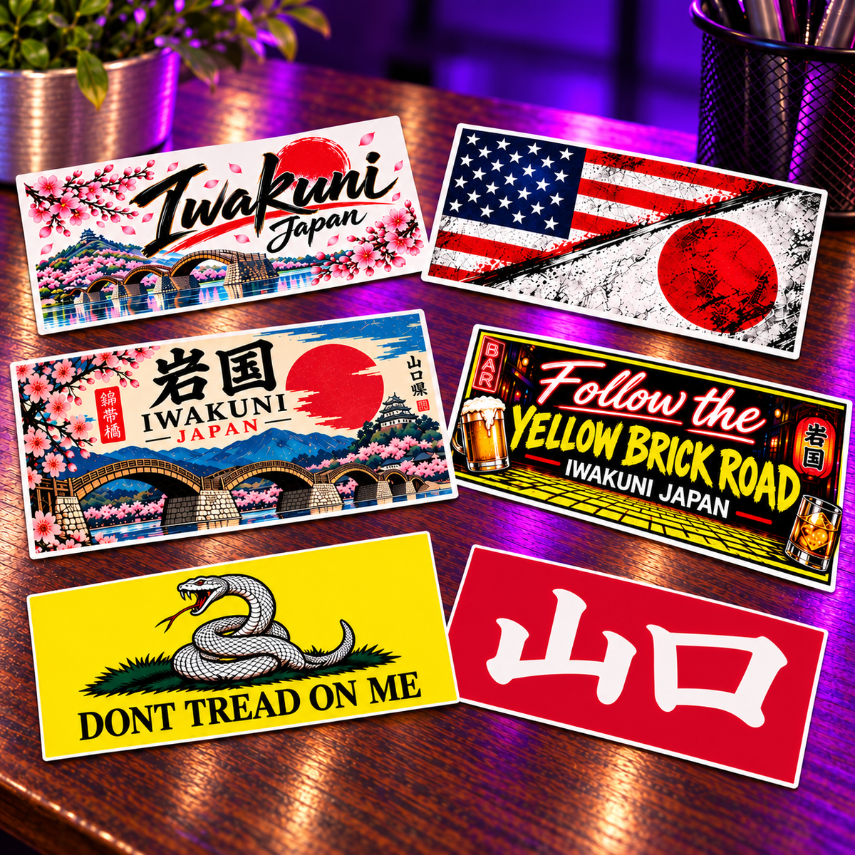 Six 2 by 4 inch rectangular sticker designs on the purple-lit wooden desk